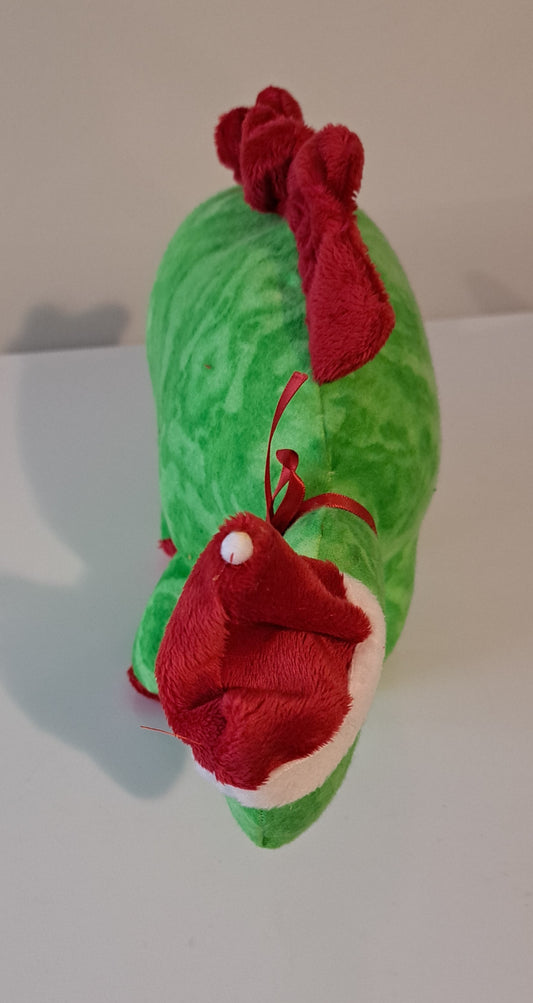 A green plush toy shaped like a stylized bird or creature, decorated with red fabric accents and a white trim around the beak area, photographed against a plain light background.