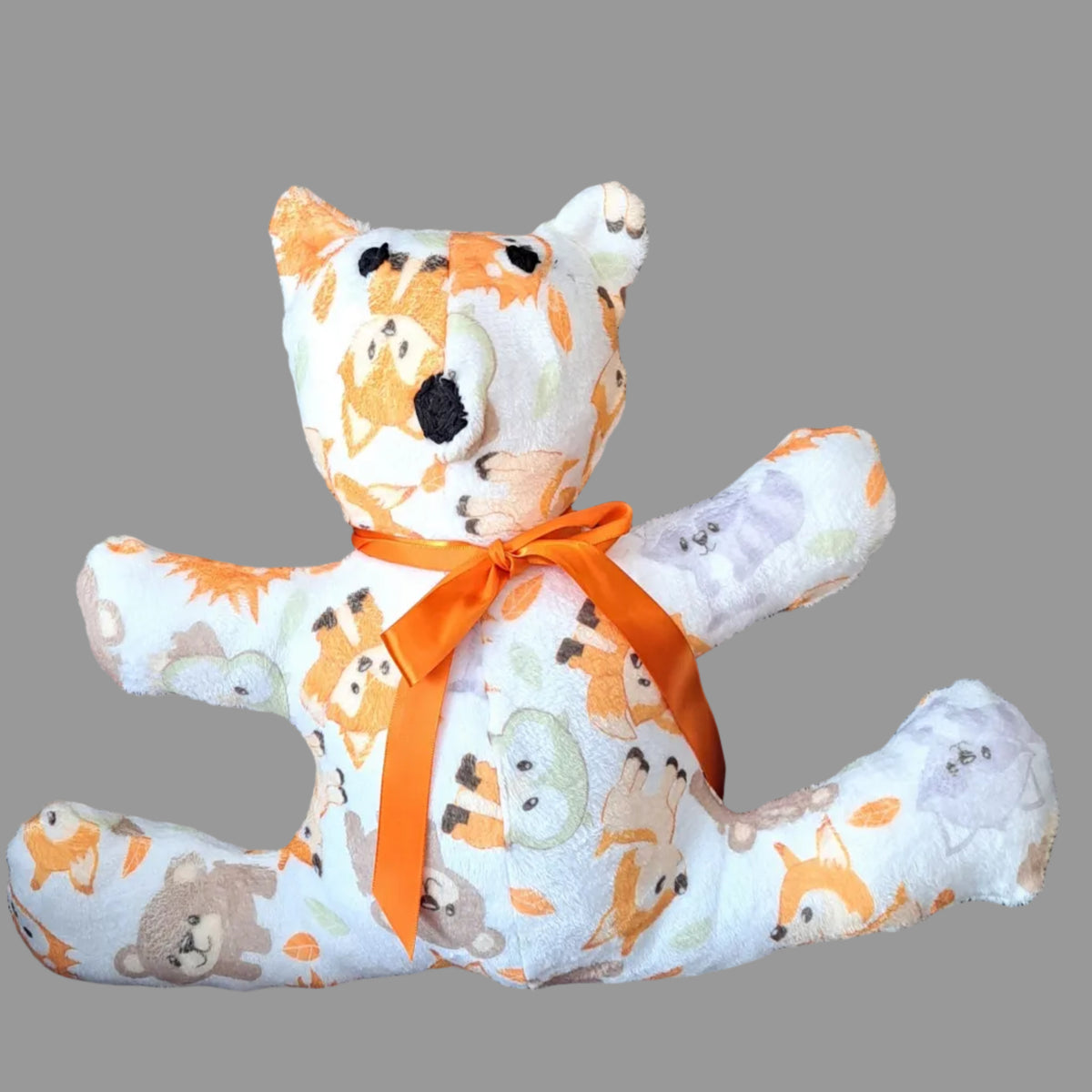 Flannel teddy with arms outstretch to 17", white background with woodland animals design, orange ribbon hand embroidered eyes & nose, safe for all ages